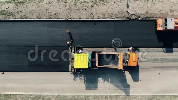 沥青被放置在顶部的道路上施工工人在道路上施工视频的预览图