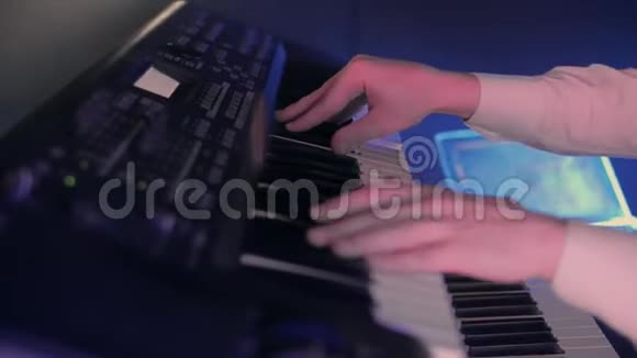 钢琴家的特写他的手在蓝色灯光的舞台上用键盘弹奏一首歌视频的预览图