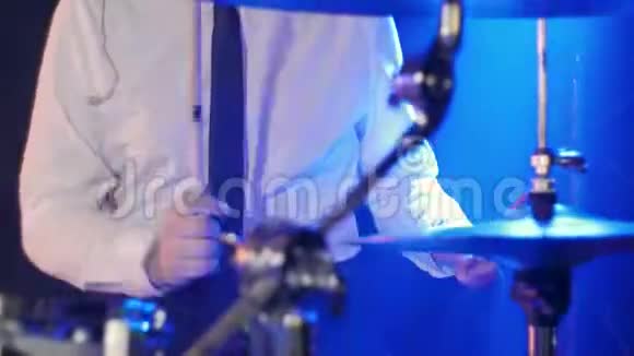 穿着白色衬衫和黑色领带的鼓手在充满蓝色的舞台上打鼓视频的预览图
