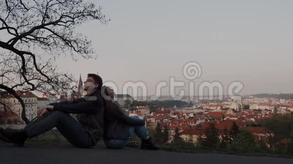 情侣们背靠背坐在观景台上可以看到布拉格的全景他们在做梦视频的预览图