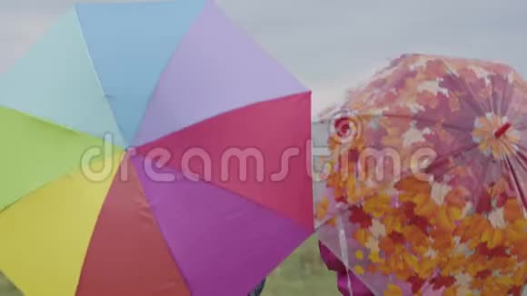 父亲和女儿举起并放下多种颜色的雨伞做鬼脸快乐的白种人家庭视频的预览图