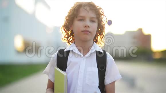 快乐可爱的聪明男孩手里拿着书包和书现代背包孩子准备回答第一次视频的预览图