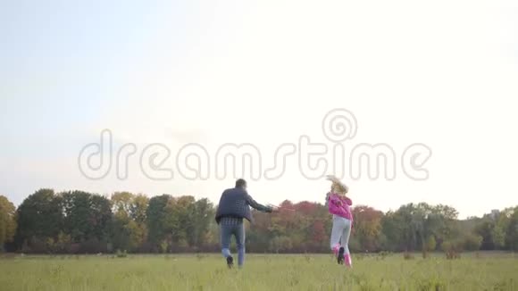 白种人的父亲和女儿在秋天的草地上奔跑用粉红色的玩具飞机模仿它的飞行幸福家庭视频的预览图