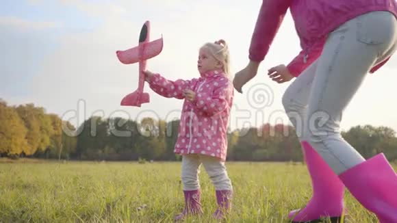 年轻的白种人女孩帮助她可爱的妹妹玩一架粉红色的玩具飞机一个金发美女视频的预览图