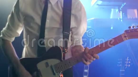 穿着白色衬衫和黑色领带的吉他手在舞台上演奏远程吉他和舞蹈视频的预览图