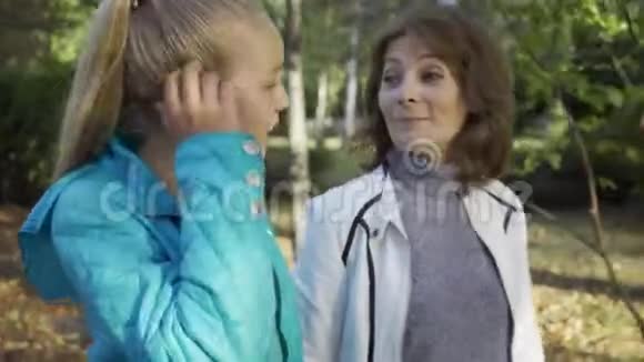 一个迷人的白种人黑发女人和一个十几岁的金发女孩交谈的特写奶奶和她在一起视频的预览图