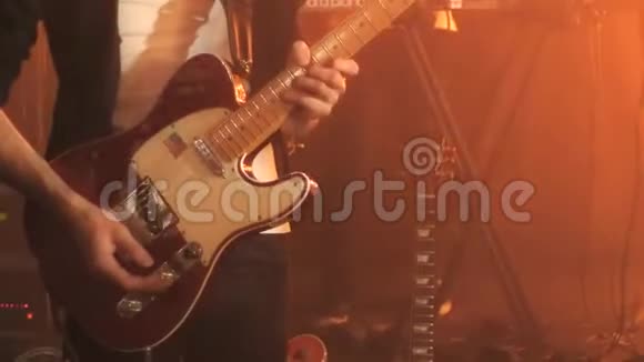 身穿黑色衬衫的吉他手在舞台上用红白吉他独奏视频的预览图
