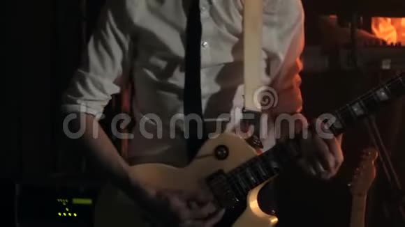 穿着白色衬衫和黑色领带的吉他手轻轻地用白色吉他弹奏和弦视频的预览图