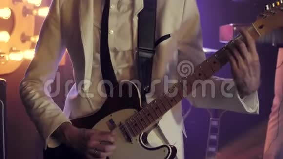 穿着白色西装和黑色领带的吉他手在舞台上用吉他快速独奏视频的预览图