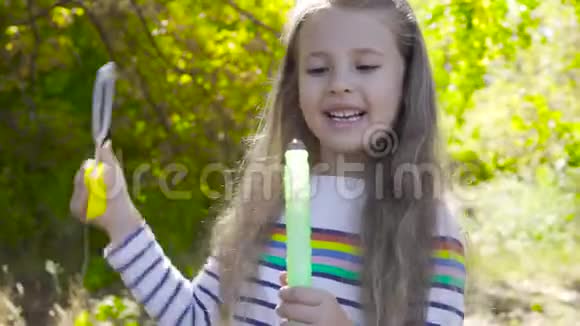深褐色头发的小女孩在秋天晒太阳吹肥皂泡穿条纹夹克的小孩视频的预览图
