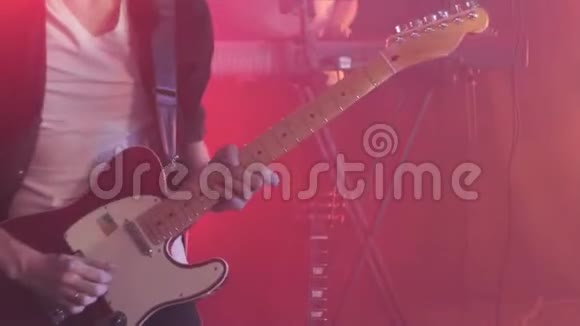 穿黑色衬衫的吉他手在舞台上用手指弹奏电吉他视频的预览图