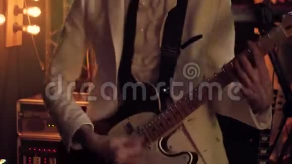 穿着白色西装和黑色领带的吉他手在舞台上用吉他快速独奏视频的预览图
