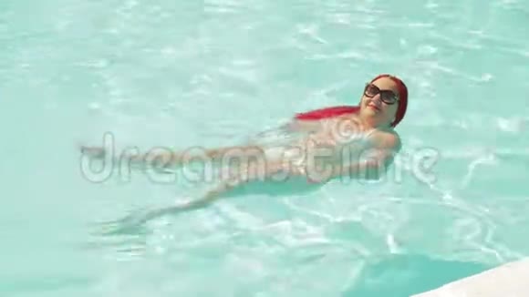 一个穿着白色泳衣的年轻女子在背后的游泳池里游泳视频的预览图