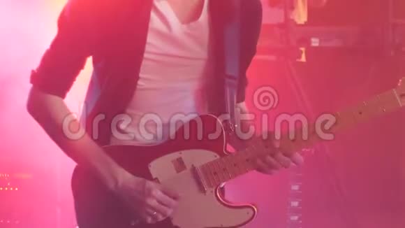 身穿黑色衬衫的吉他手在舞台上用粉红色的闪光挑手视频的预览图
