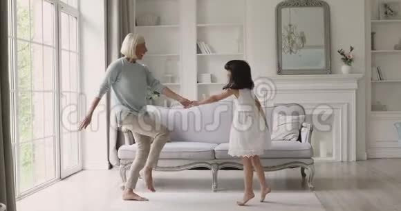可爱的孙女和成熟的奶奶在客厅跳舞视频的预览图