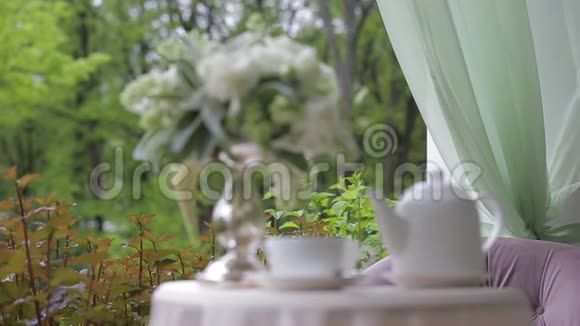 在一张装饰着的白色桌子上在一个封闭的顶部下在露天供应热的美味的一个白色茶壶视频的预览图