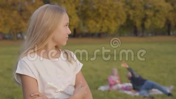 年轻的少女金发碧眼浅棕色的眼睛看着她父亲和姐姐坐在背景上视频的预览图
