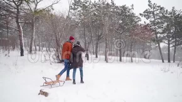 可爱的一对夫妇在下雪的冬天散步拉雪橇有女朋友的人会在下雪的时候滑雪女人要去视频的预览图