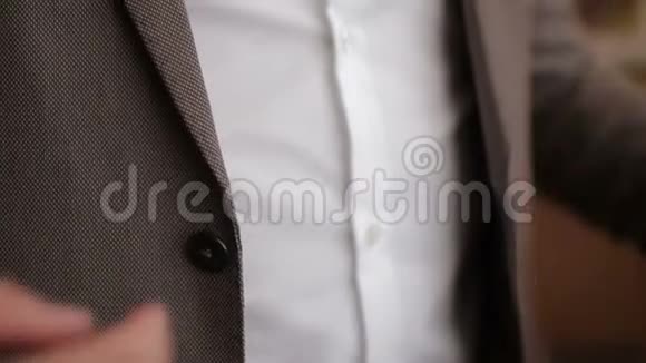 扣上一件夹克时髦的新郎穿着西装在夹克上扣上纽扣为婚礼做准备视频的预览图