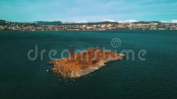 一个缓慢的飞行向一个小的岩石岛躺在海上在城市的背景下一阵微风晚冬视频的预览图