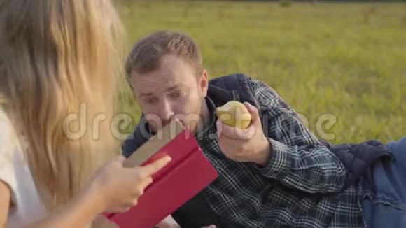 年轻的白种人在吃苹果等待他的女儿读这本书父亲和年轻人在一起视频的预览图