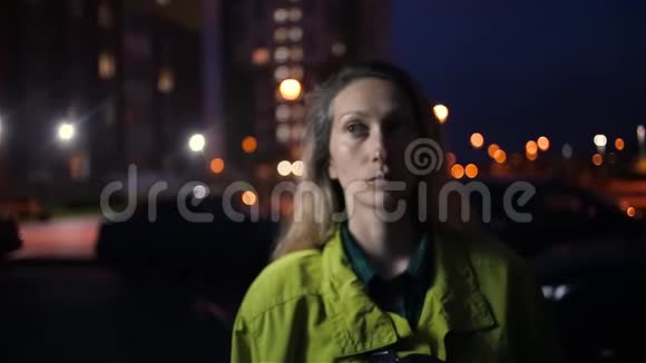 白种人女人体贴地把头发留在户外夜晚的城市灯光视频的预览图