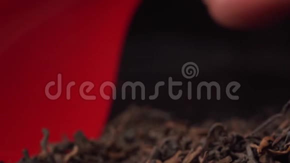 黑茶或绿茶用红色塑料勺子收集在黑桌上把茶放在一个视频的预览图