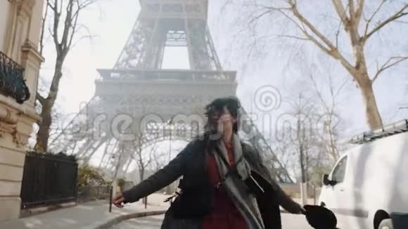 镜头跟随着幸福的美女兴奋地看到著名的埃菲尔铁塔欢快地在巴黎大街上旋转着慢动作视频的预览图