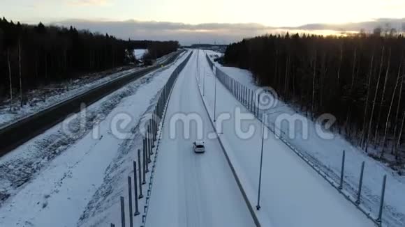 鸟瞰一辆孤独的汽车沿着一条森林雪道驶向黎明家庭用车旅行视频的预览图