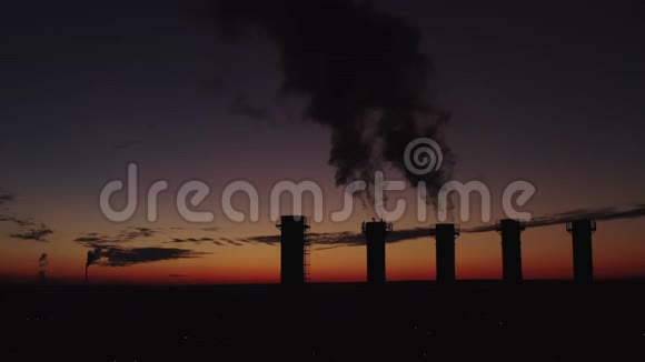 夕阳和城市背景下高高的烟囱浓烟高高升起五座冷却塔的剪影视频的预览图