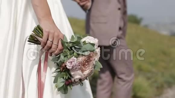 新娘和新郎走着牵着手新娘带着一束粉红色的玫瑰视频的预览图