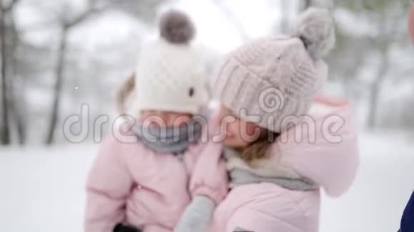 在雪天的圣诞节假期妈妈带着女儿穿连身衣穿着粉色连衣裙和婴儿一起走路的女人视频的预览图
