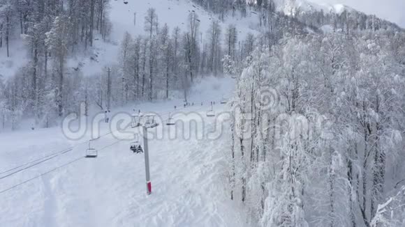 人们骑在滑雪场和滑雪板上冬季度假索道上的空中观景椅升降无人机观景胜视频的预览图