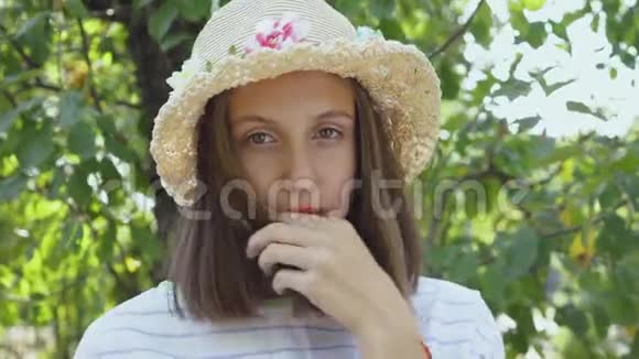 一位年轻女子在公园里看相机的特写肖像戴着草帽的美丽白种人女孩休闲视频的预览图