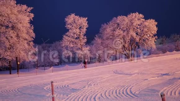 美丽的夜景可以看到滑雪坡和霜冻中的灯光和树木视频的预览图