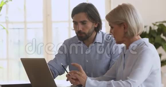 男性经理导师帮助成熟女性客户解释计算机软件视频的预览图