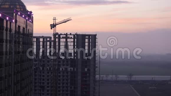 塔吊向侧移动未完工的房子靠在夕阳的天空建筑工地嗨正在施工的崛起大厦R视频的预览图