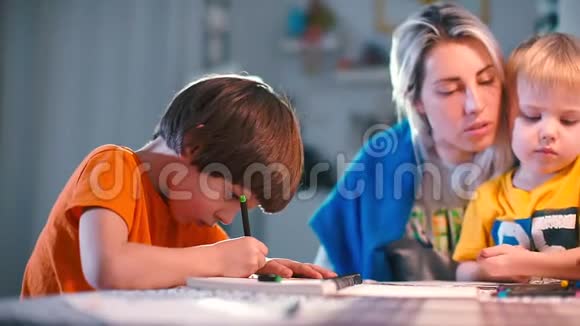 两个男孩在学校的一张桌子上用一支女铅笔在纸上画画视频的预览图
