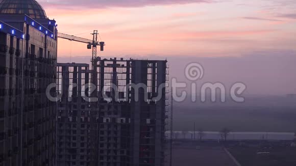 塔吊向侧移动未完工的房子靠在夕阳的天空建筑工地嗨楼在建视频的预览图