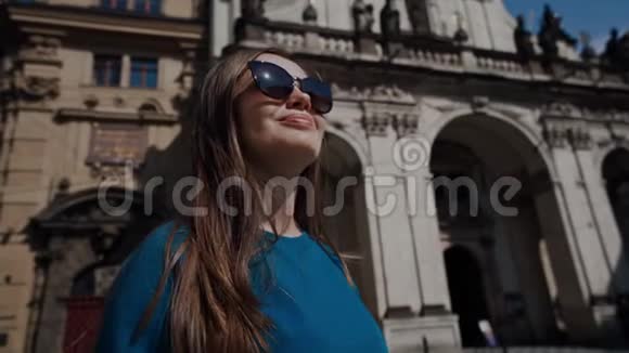戴墨镜的漂亮女孩站在广场上在历史上巴洛克建筑的背景下近距离观看视频的预览图