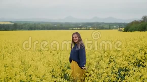美丽的女人站在黄色的花田里双臂张开视频的预览图