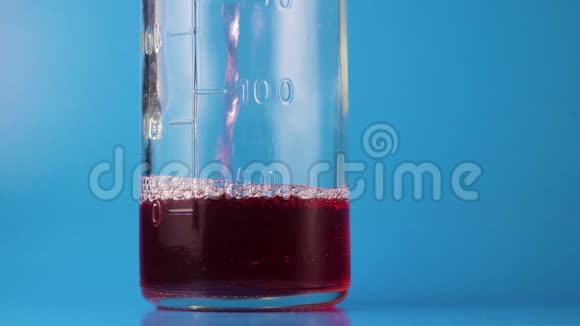 粉红色液体的电影胶片倒入深蓝色背景的玻璃量瓶中视频的预览图