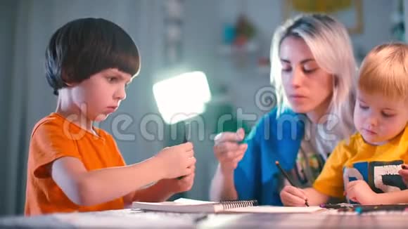 两个带老师的男孩在幼儿园的一张桌子上画纸视频的预览图