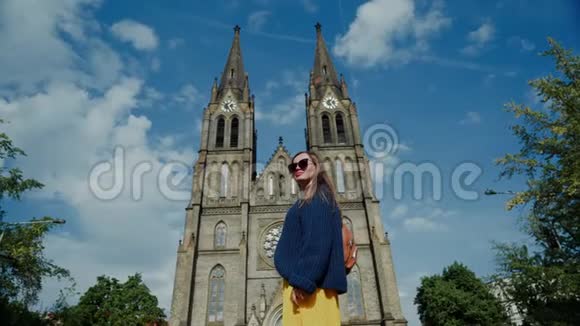 戴墨镜的漂亮女孩站在圣路德米拉新哥特教教堂的背景上镜头从后面低下来视频的预览图