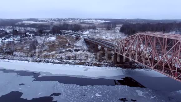 从火车后面的无人机在结冰的河流上的桥上追踪空中视野视频的预览图