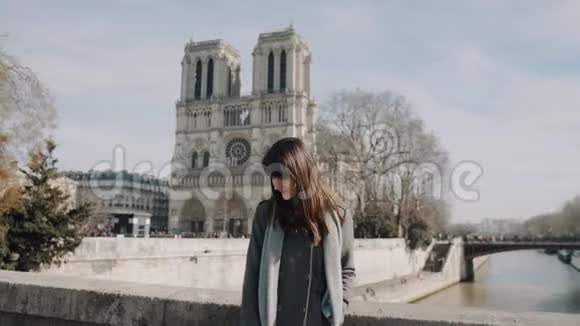 快乐优雅美丽的女人摆在令人惊叹的巴黎圣母院大教堂附近享受晴朗的晴天慢动作视频的预览图