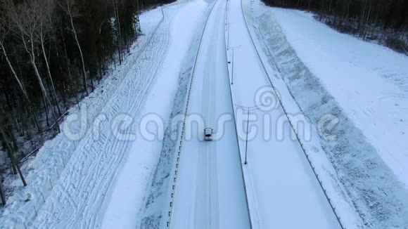 鸟瞰一辆孤独的汽车沿着一条森林雪道驶向黎明家庭汽车旅行视频的预览图