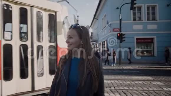 美丽的女孩站在街的十字路口在经过红色复古电车和微笑的背景下布拉格捷克视频的预览图