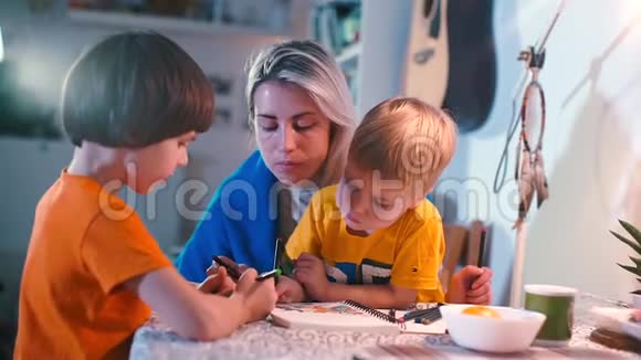 两个男孩在厨房的一张桌子上和妈妈画了一幅画视频的预览图