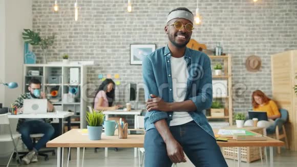 富有创造力的非裔美国人戴着滑稽眼镜在办公室微笑的肖像视频的预览图